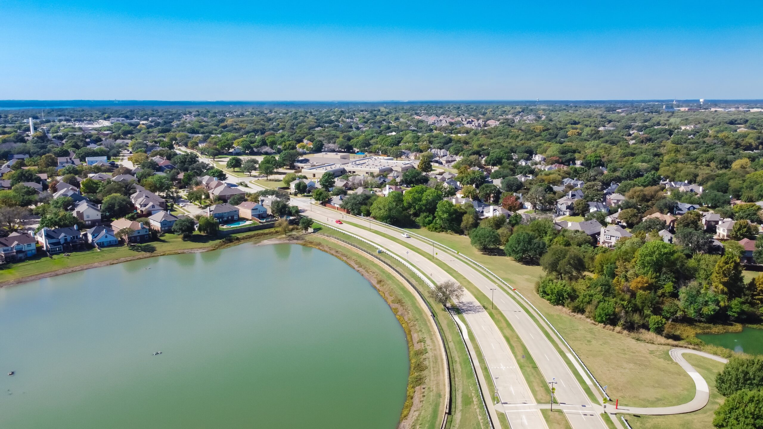 Grapevine Lake with homes in the background, featuring green and weed-free lawns, emphasizing the quality of Flower Mound Lawn Care and Flower Mound Mosquito Control.