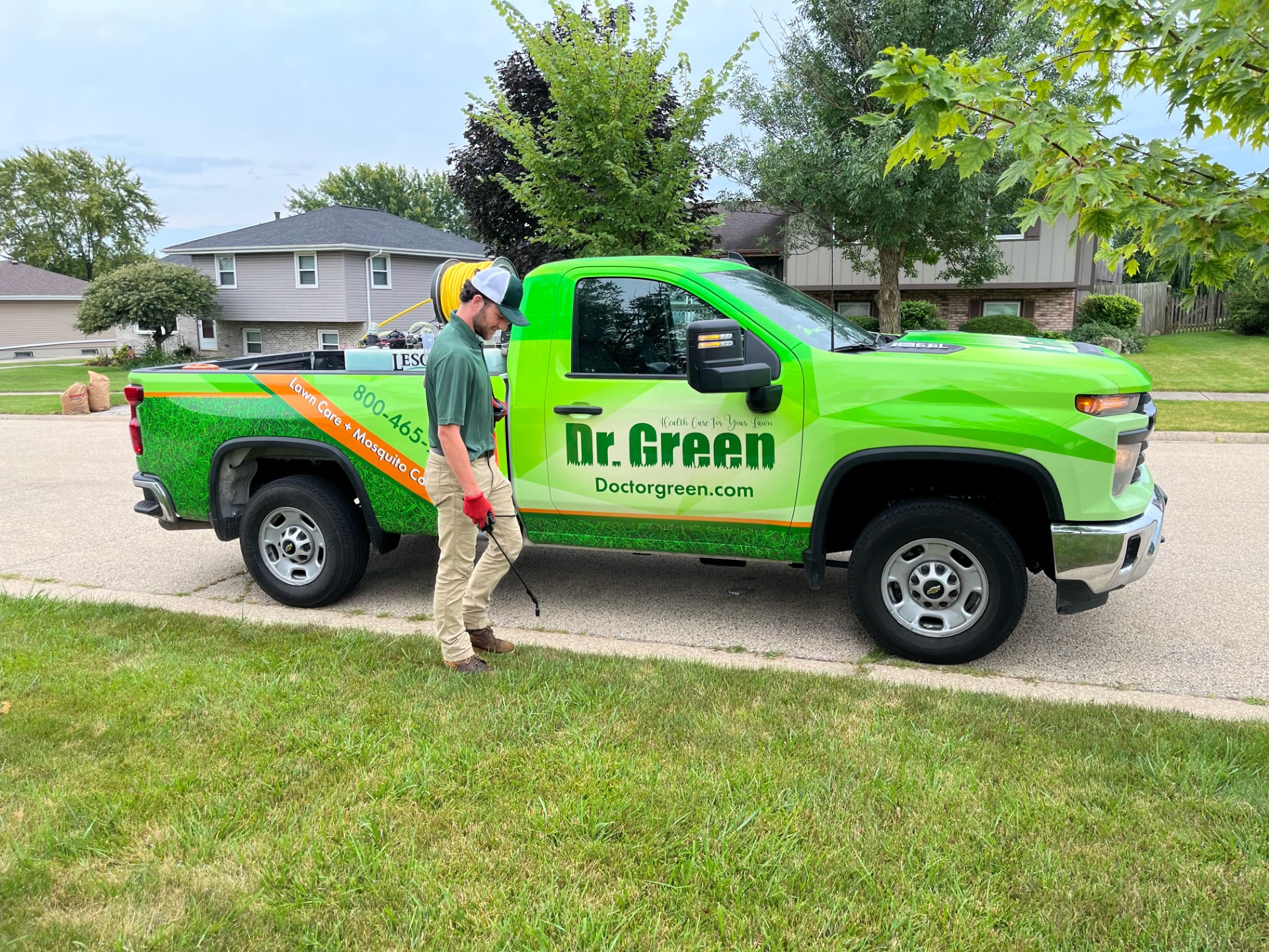 Certified Technician from Crown Point Lawn Care treating a green and weed-free lawn.