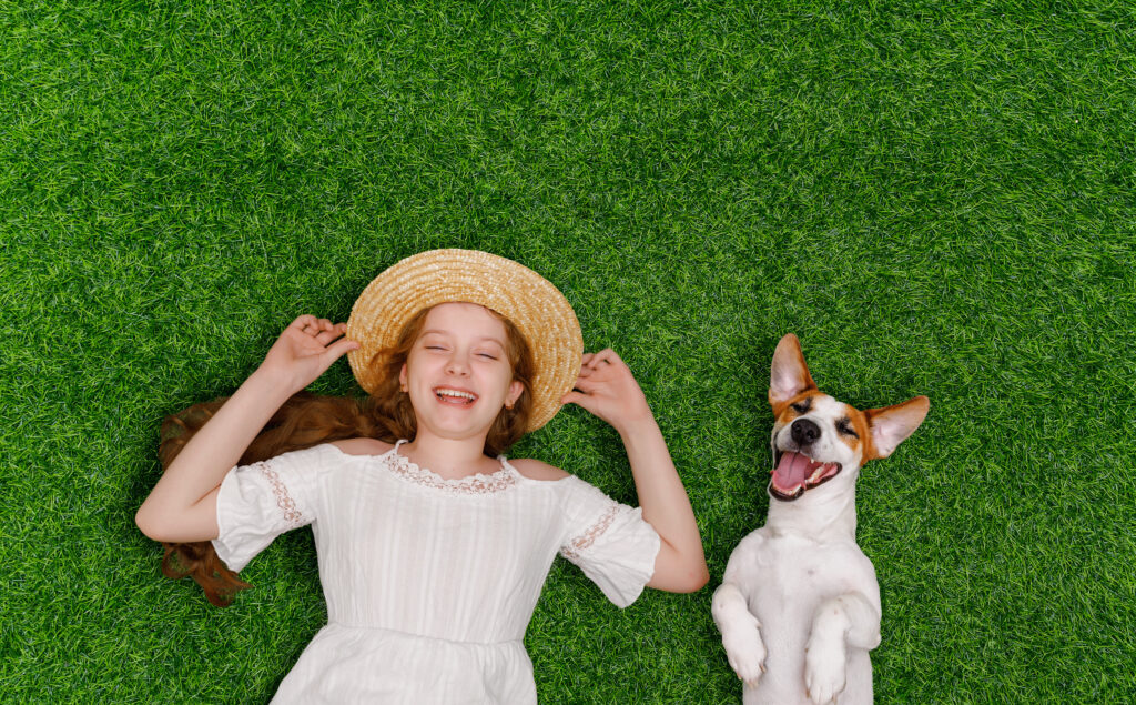 Girl and dog relaxing on a thick, weed-free lawn after professional weed control