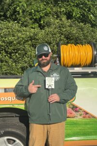 Dr. Green Services technician standing beside branded weed control truck. 