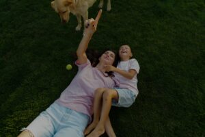 Mother and child lying on a green lawn with their dog enjoying pet safe lawn care.