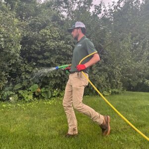 Technician applying liquid aeration to improve soil penetration in lawn aeration science