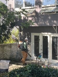 Dr. Green Services technician applying exterior pest control perimeter treatment around a home