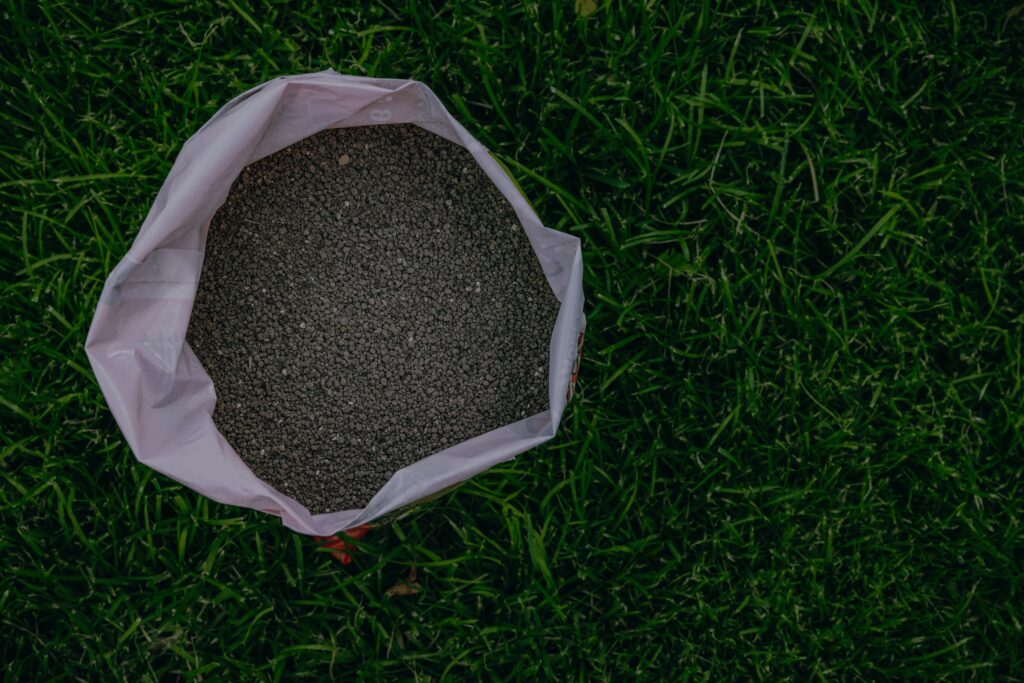 Bag of early spring bluegrass fertilizer sitting on a thick green Kentucky bluegrass lawn in Illinois